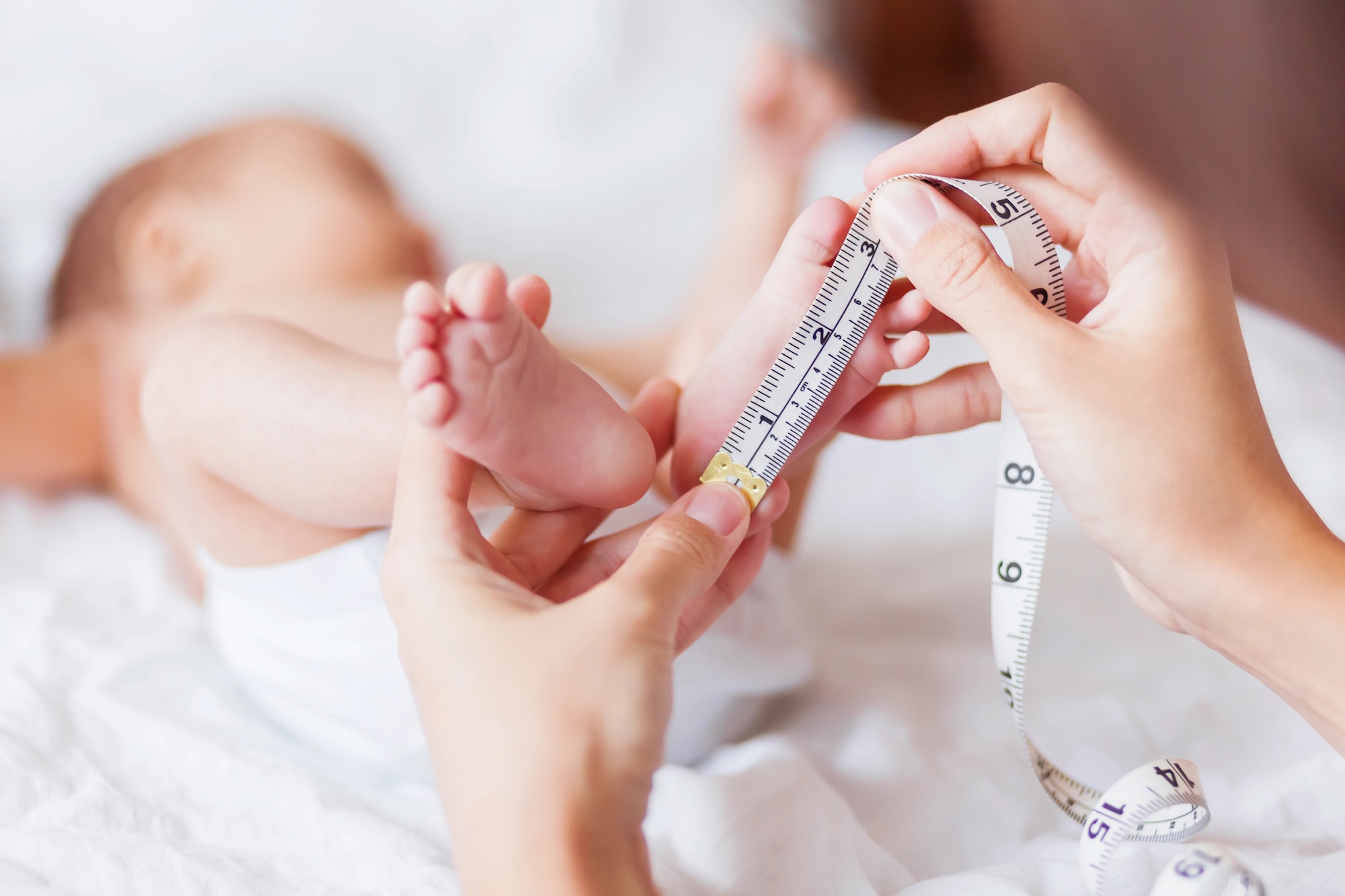 Mutter misst Babyfuß mit Maßband